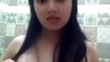 Sex model stands in front of mirror and squeezes own big natural tits